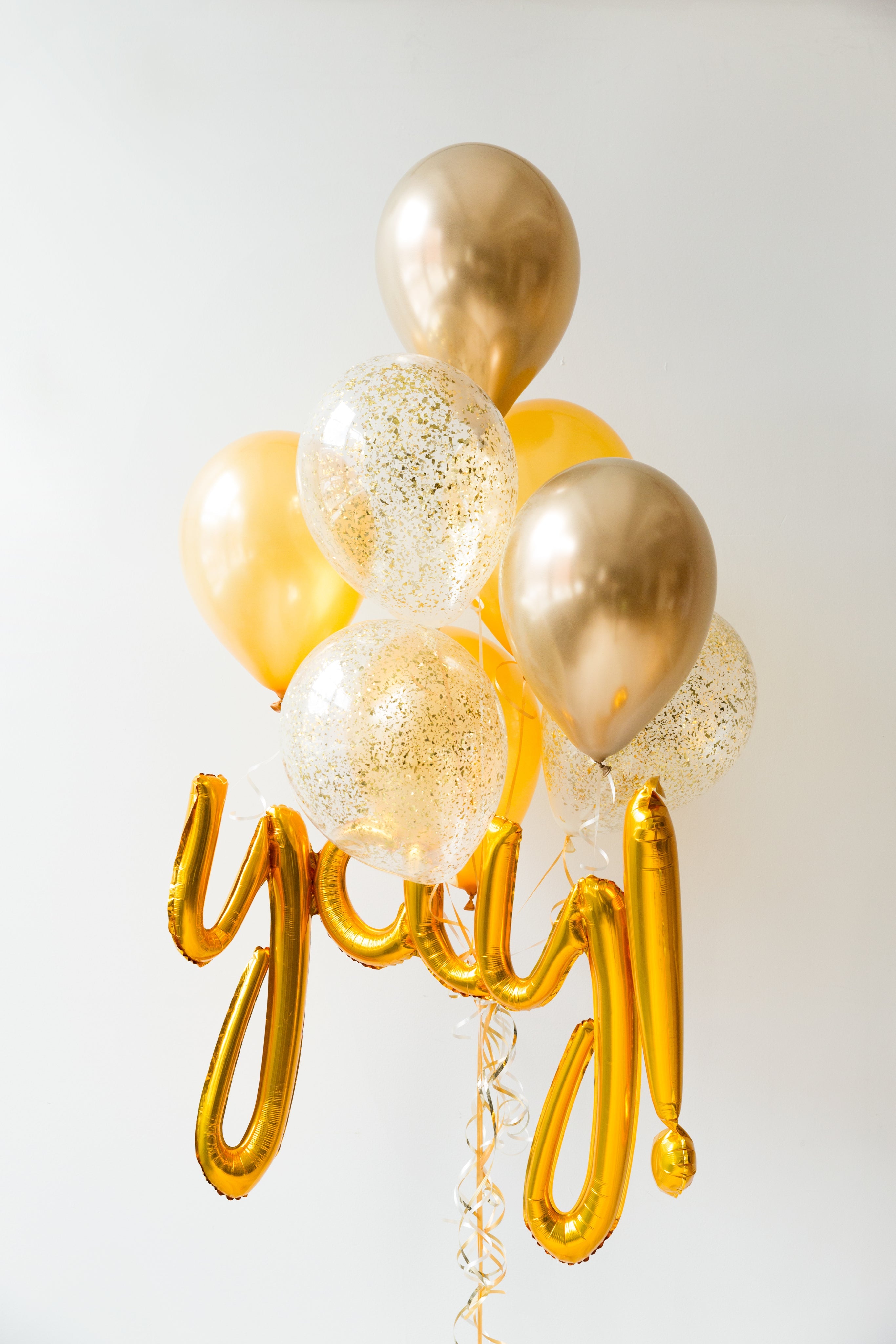 Colorful balloon bouquet with gold and clear balloons featuring a golden 'yay!' for celebrations and achievements