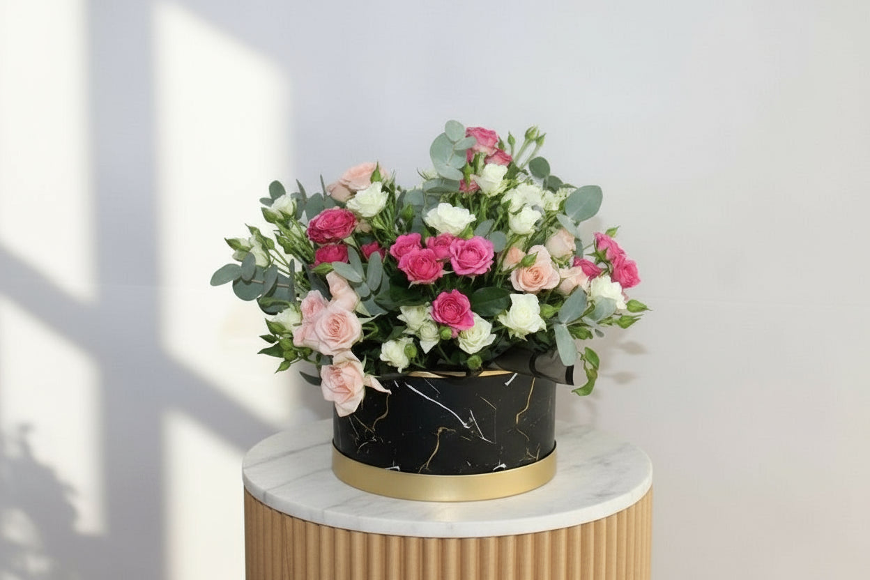 Bouquet of pink and white flowers in a black container on a light gray background
