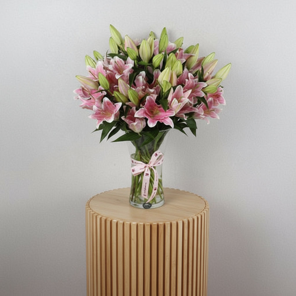 Lilliam Oriental flowers 10 pieces in a clear vase with a decorative ribbon