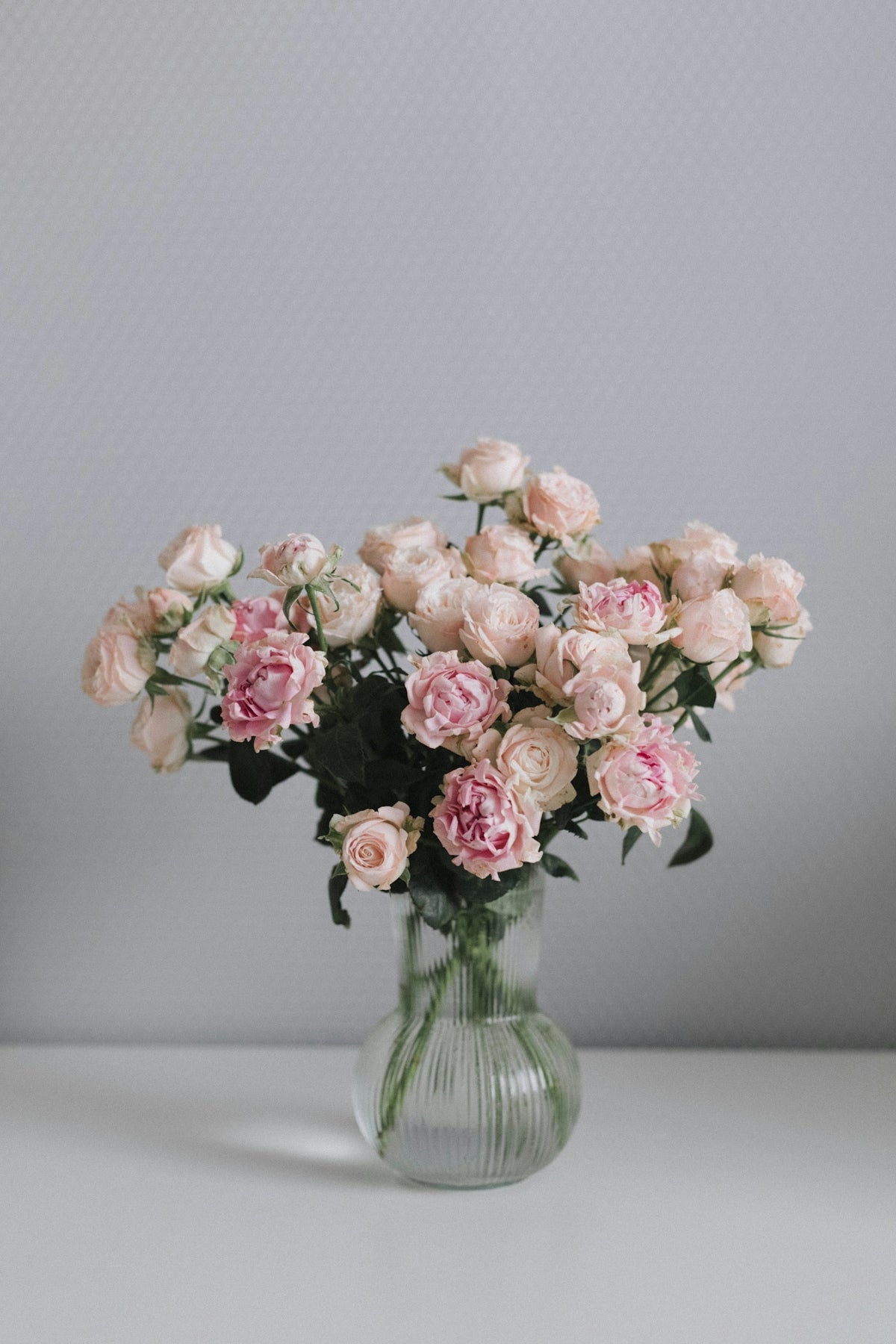a glass vase filled with pink roses on a table
