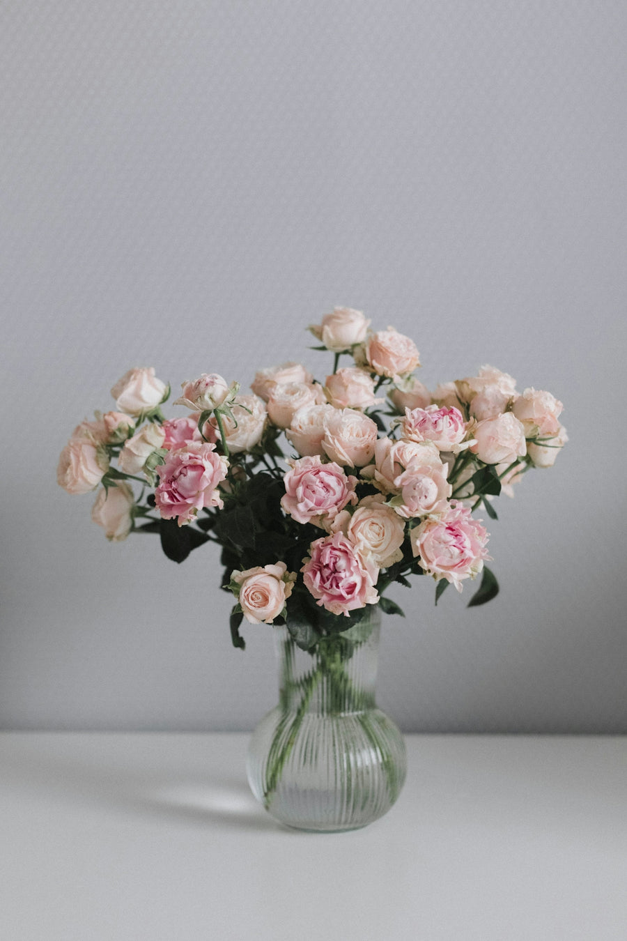a glass vase filled with pink roses on a table