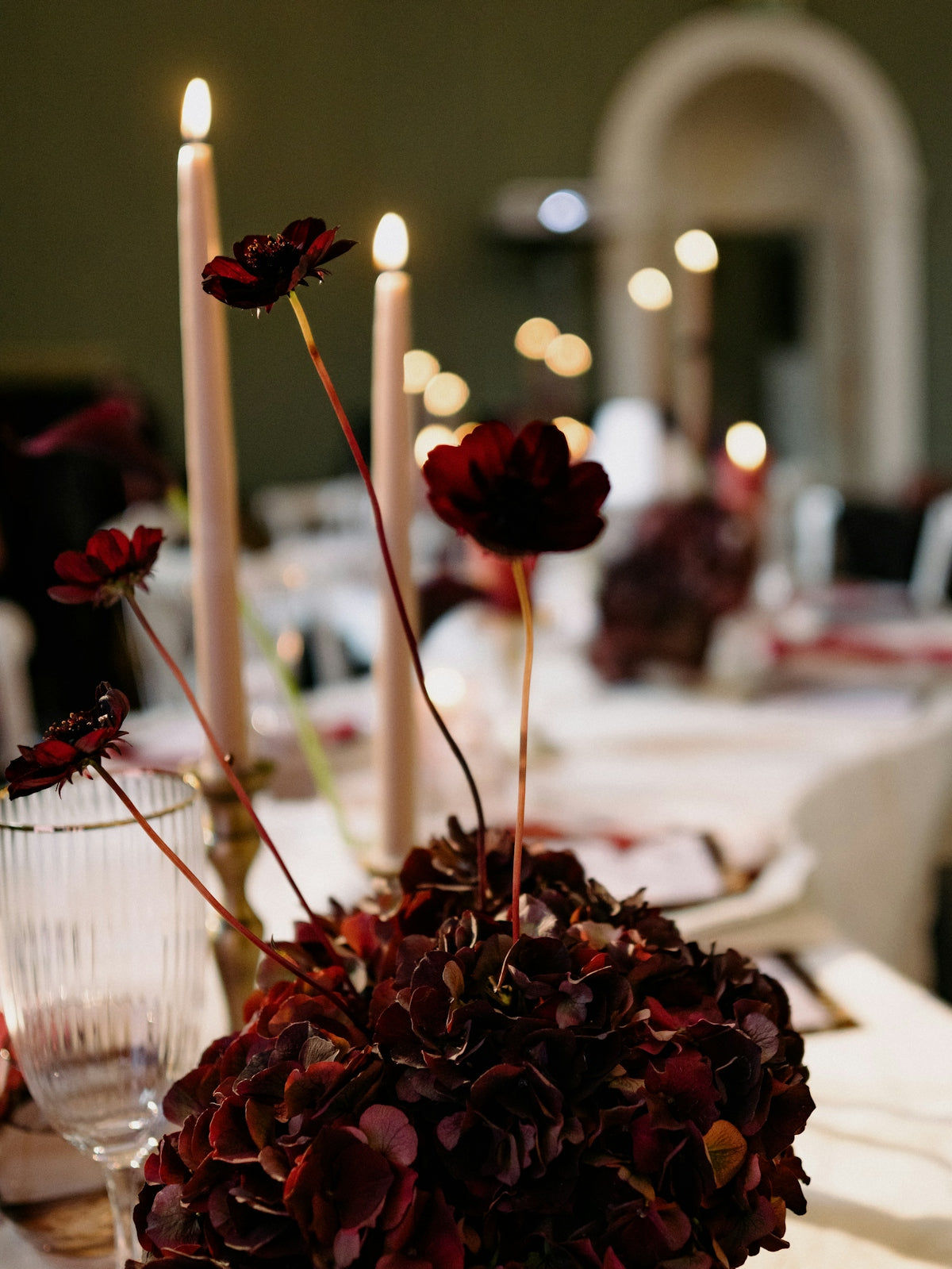 Dark red flowers and tall candles on a table