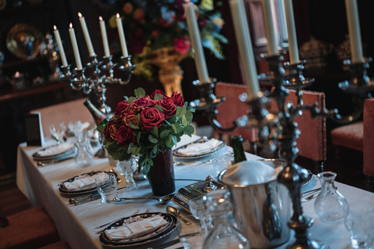A formal dining table set with candelabras and red roses.