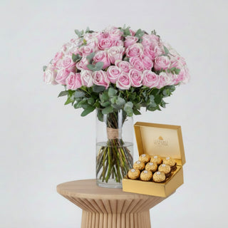 Bouquet of pink roses in a clear vase with a pink ribbon on a white background