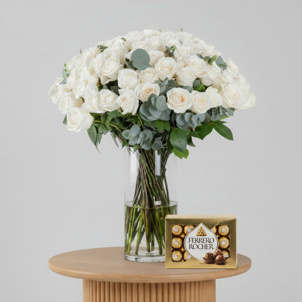 Bouquet of white roses with greenery in a clear vase on a white background