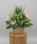 Bouquet of flowers in a woven basket against a plain background