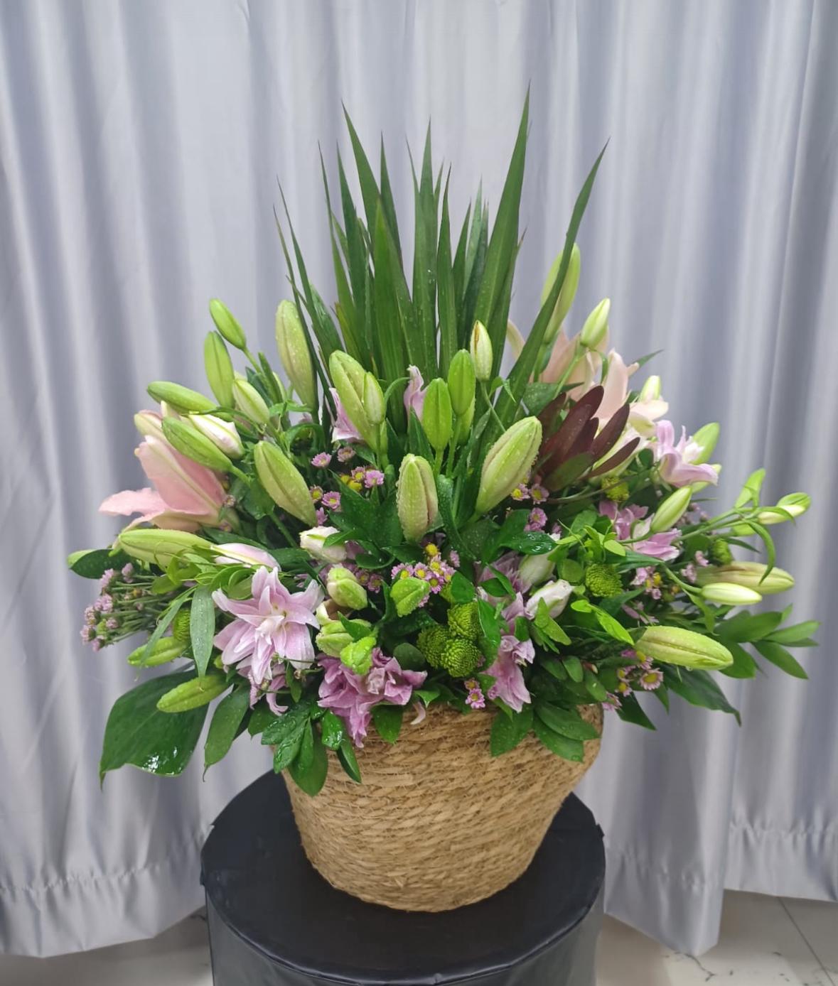 Bouquet of flowers in a woven basket against a plain background