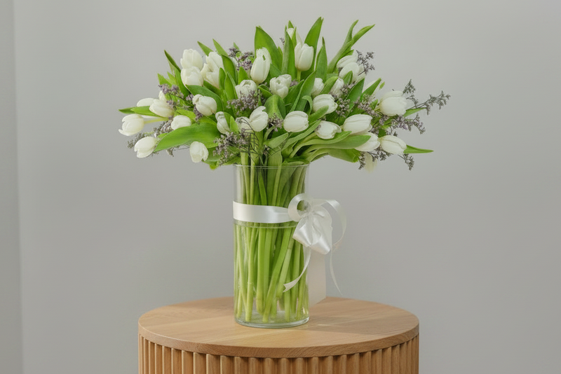 Bouquet of 40 white tulips in a clear vase with a white ribbon