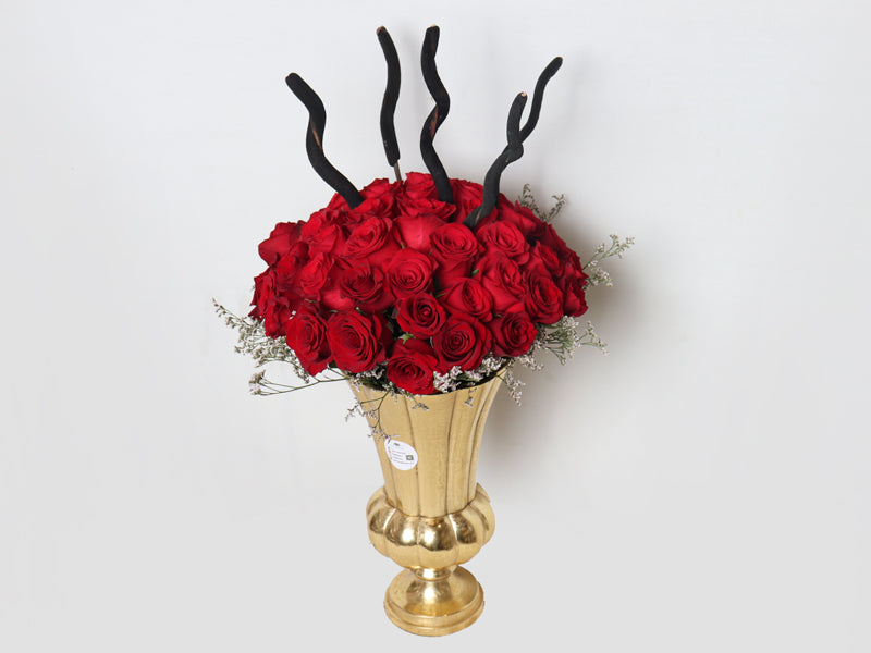 Stunning arrangement of 50 red roses in a gold vase with decorative black accents
