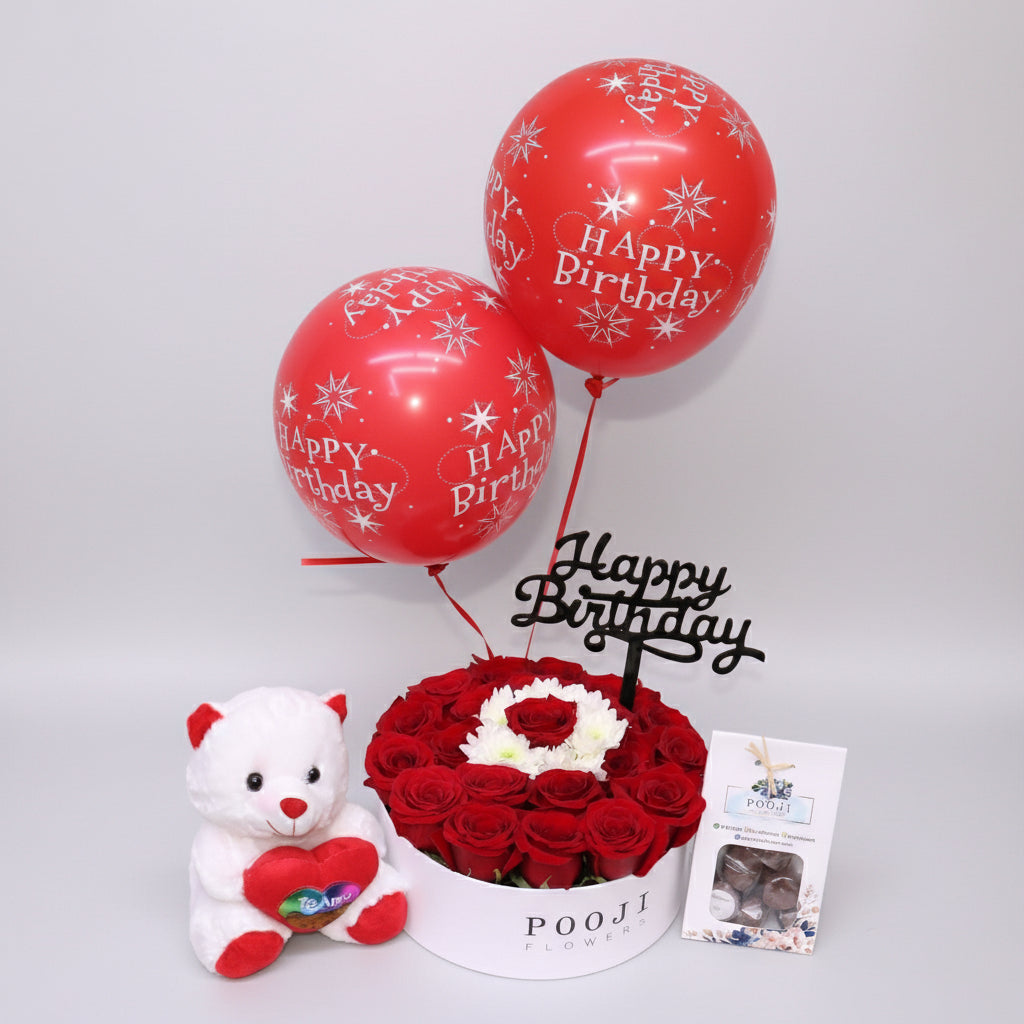 Birthday arrangement with red balloons, flowers, and a teddy bear on a light background