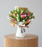 Bouquet of pink and white tulips wrapped in brown and white paper