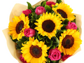 Bouquet of sunflowers and pink roses in a beige paper wrap on a white background