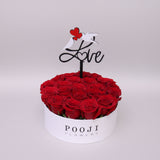 Box of red roses with a 'Love' sign and 'Pooji Flowers' branding