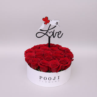 Box of red roses with a 'Love' sign and 'Pooji Flowers' branding