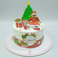 Christmas-themed birthday cake with a child figurine and decorations on a white background