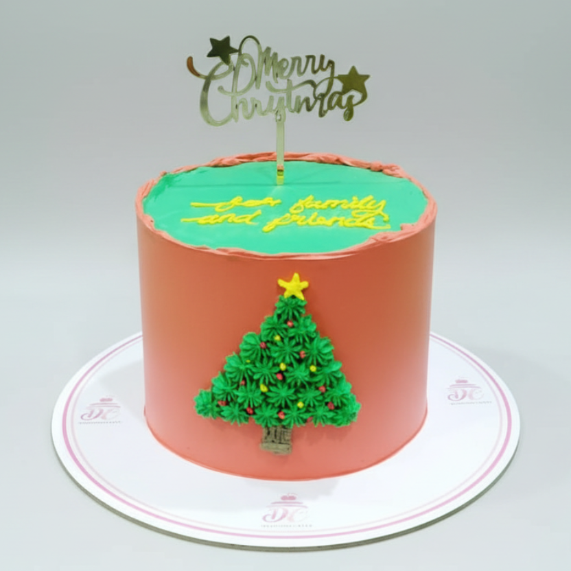 Christmas-themed cake with green icing, a Christmas tree decoration, and 'Merry Christmas' topper.