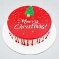 Christmas-themed cake with red icing, white text, and a green tree decoration on a white background.