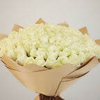 Bouquet of white roses wrapped in brown paper