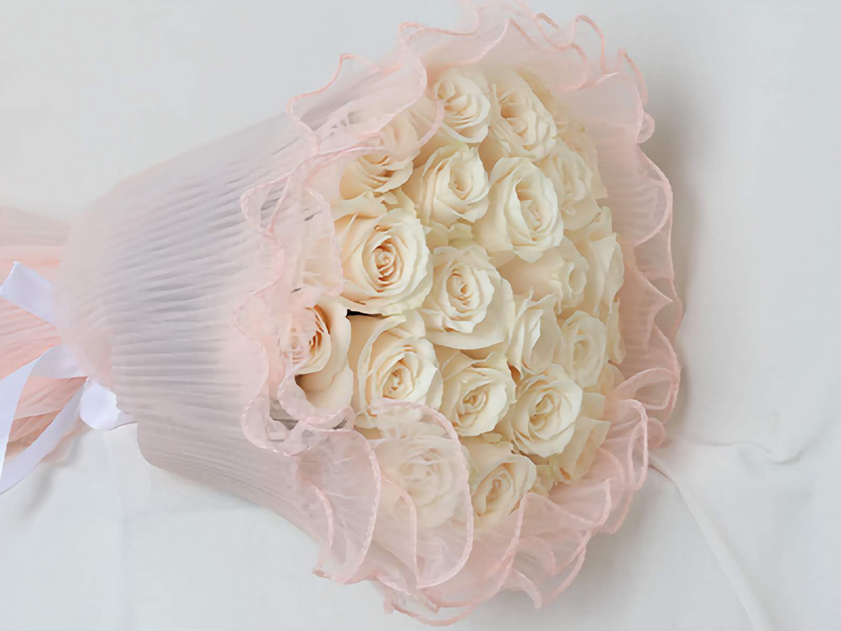 Hand bouquet containing white roses with pink wrapping paper.