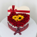 Heart-shaped flower arrangement with red roses and sunflowers on a white background