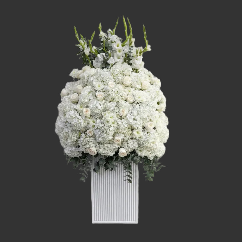 White floral arrangement in a rectangular white vase on a light gray background