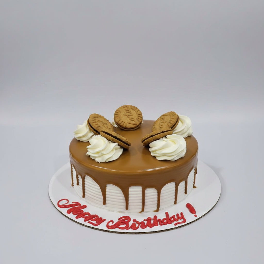 A round birthday cake with glossy brown chocolate glaze, decorated with white piped cream swirls and five biscuit cookies. The cake sits on a white board with 'Happy Birthday!' written in red icing, photographed on a gray metal surface.