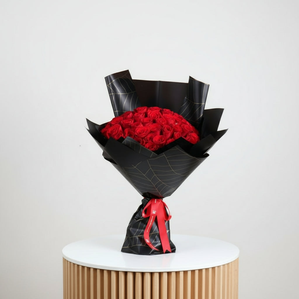 Bouquet of red roses wrapped in black paper with a red ribbon on a white background