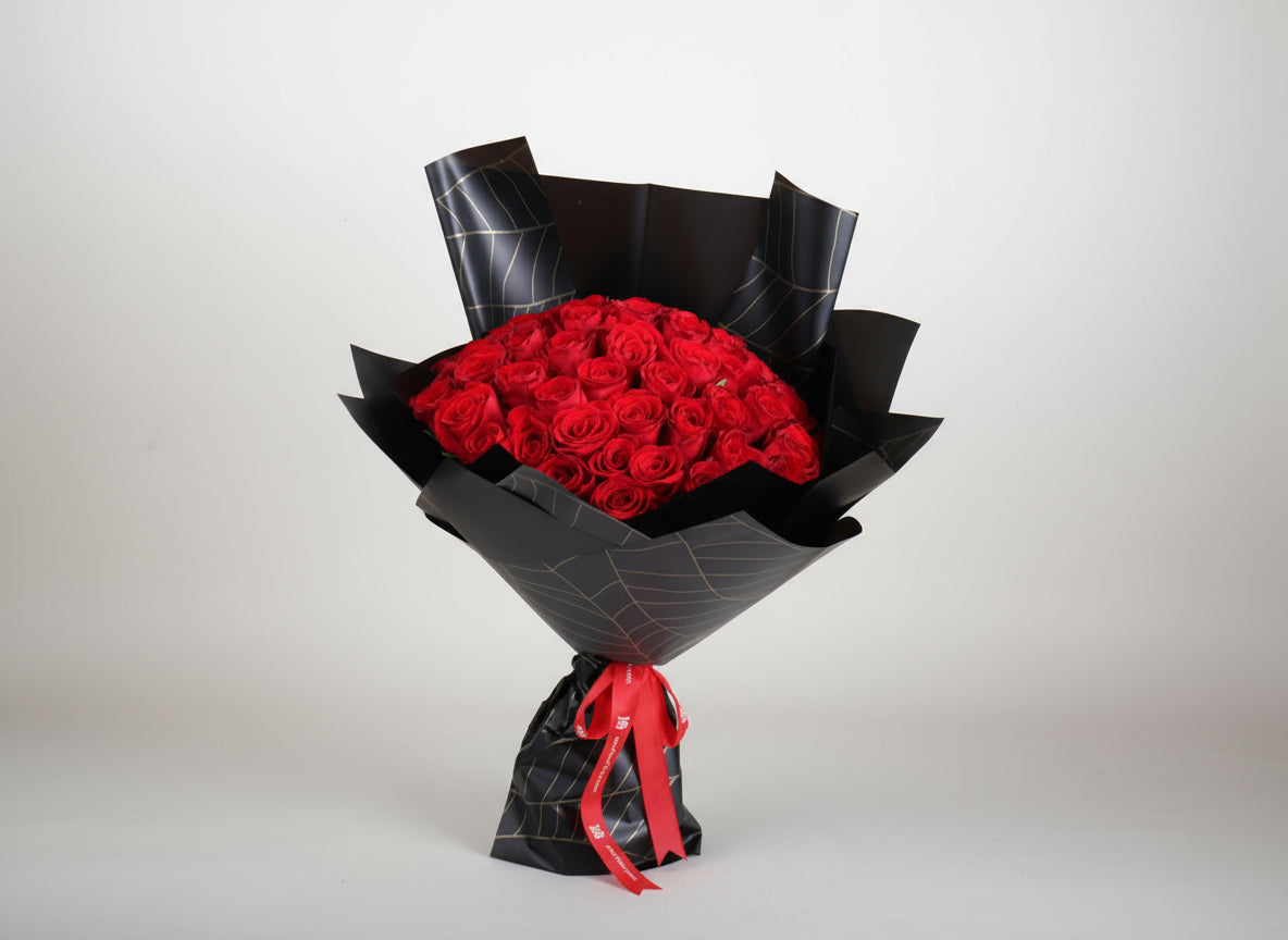 Bouquet of red roses wrapped in black paper with a red ribbon on a white background