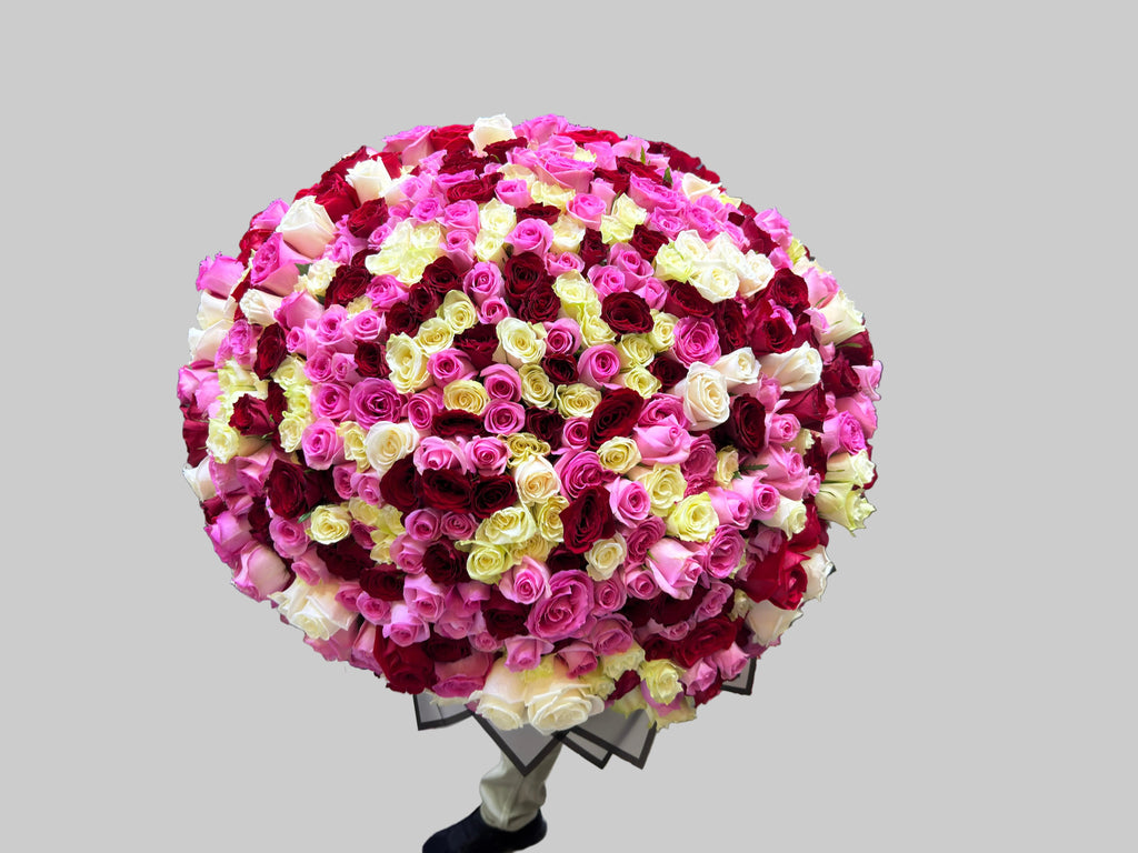 Person holding a large bouquet of pink, red, and white flowers in an indoor setting.