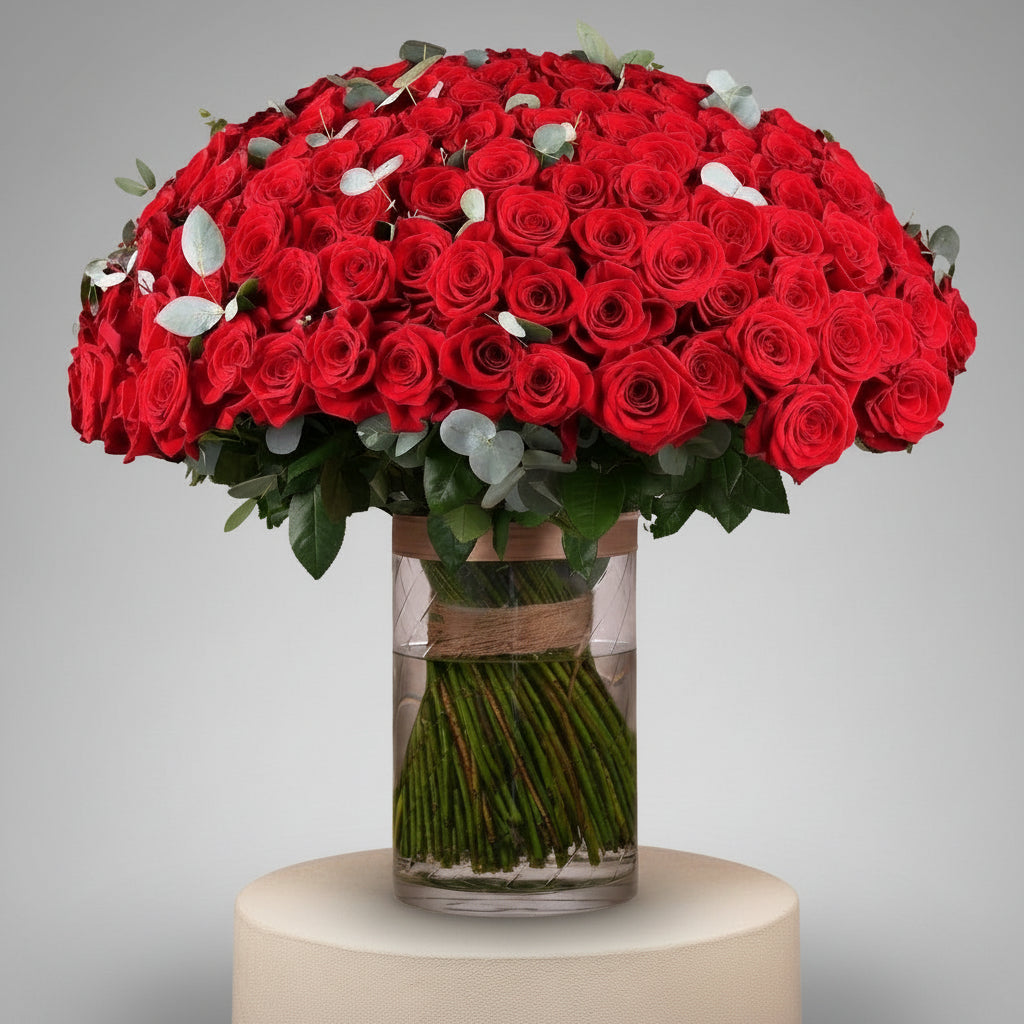 Bouquet of red roses in a clear vase with a beige ribbon