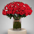 Bouquet of red roses in a clear vase with a beige ribbon