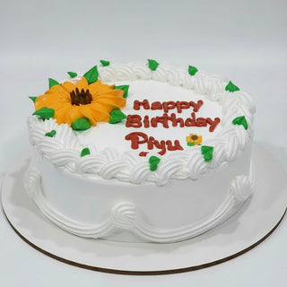 Birthday cake with white frosting, sunflower decoration, and 'Happy Birthday Piyu' text on a white background