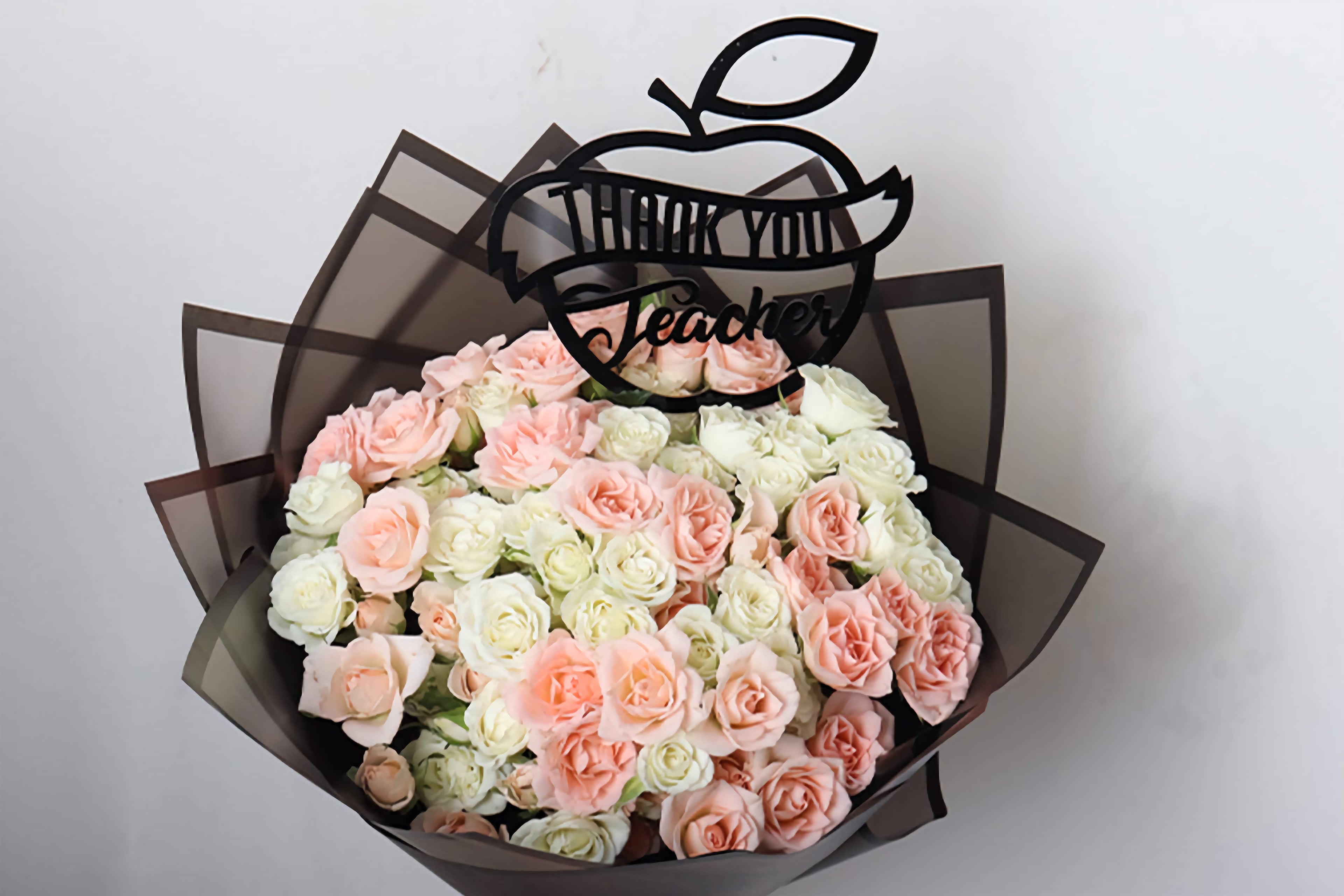 Bouquet of pink and white roses with a 'Thank You Teacher' apple decoration on a white background