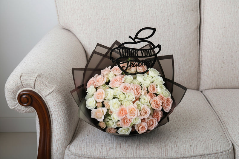 Bouquet of pink and white roses with a 'Thank You Teacher' apple decoration on a white background