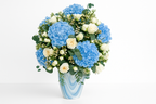 Bouquet of blue hydrangea and white rose flowers in a vase on a white background