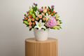 Bouquet of colorful flowers in a white vase on a light background