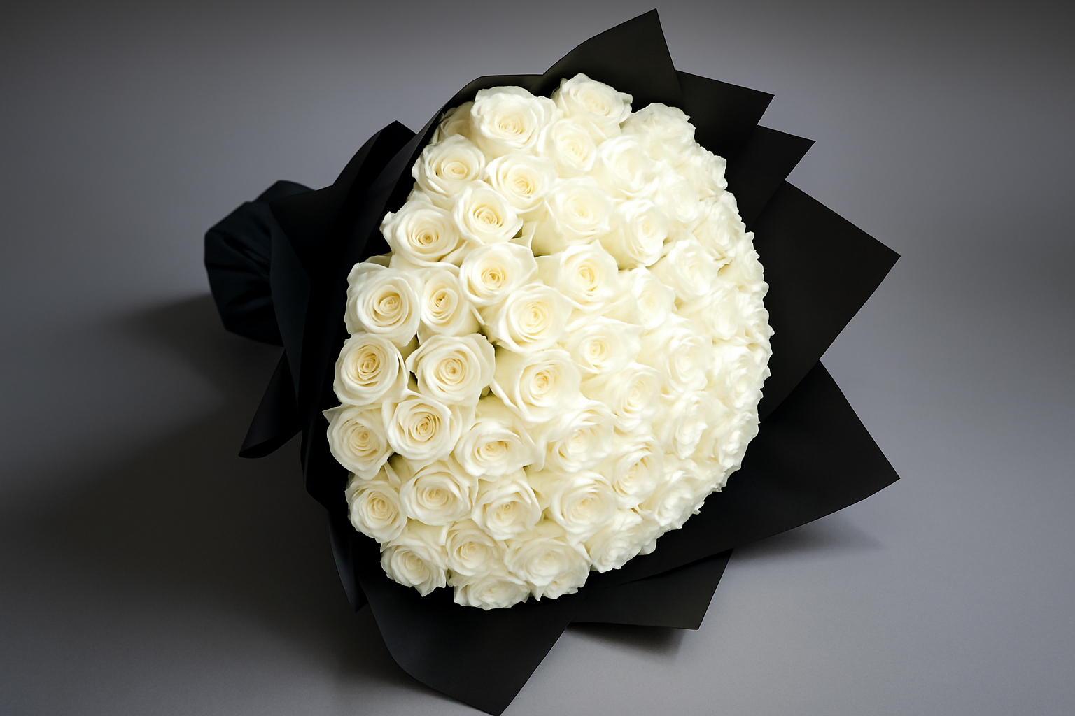 Bouquet of white roses wrapped in black paper on a gray background