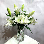 Elegant white lilies bouquet in a glass vase by Pooji Flowers with a decorative ribbon