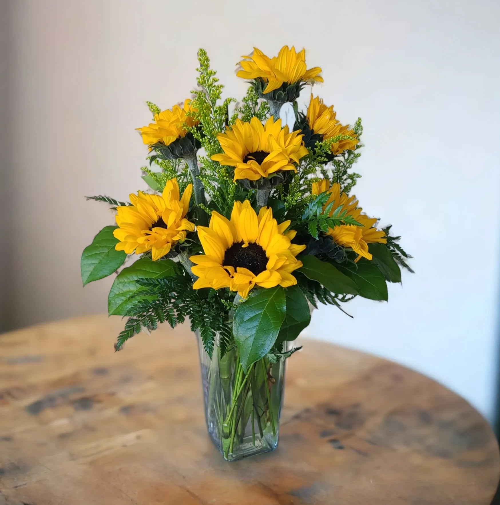 Bright bouquet of sunflowers arranged with greenery in a glass vase for a cheerful home decor