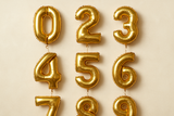 Gold helium balloons in the shape of numbers 0 through 9 in a square format