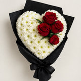 Top-down view of the heart-shaped bouquet with white chrysanthemums and red roses in black wrapping