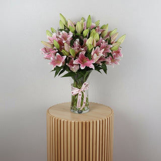 Lilliam Oriental flowers 10 pieces in a clear vase with a decorative ribbon