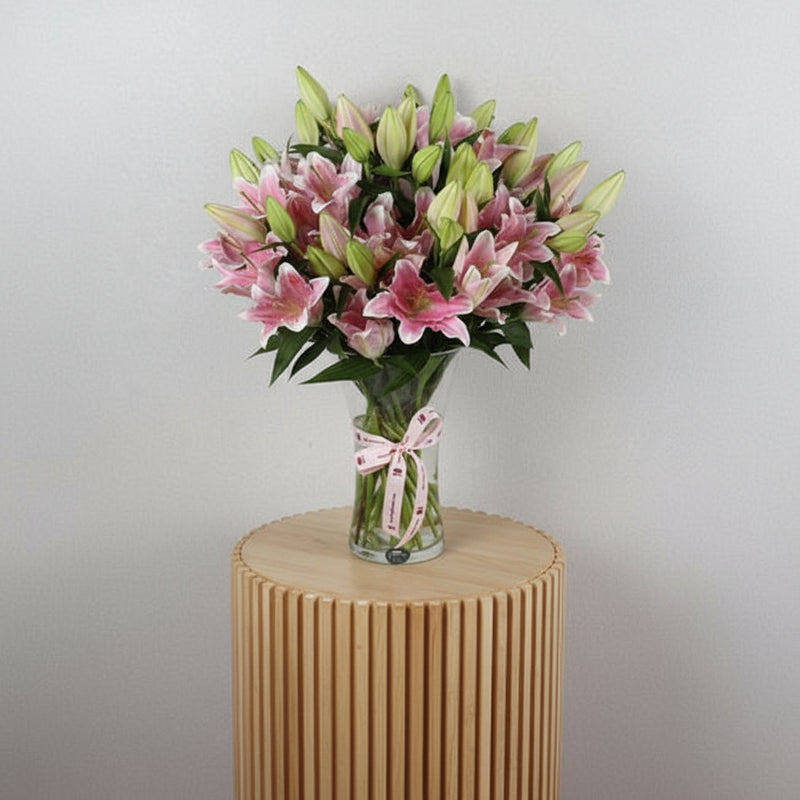 Lilliam Oriental flowers 10 pieces in a clear vase with a decorative ribbon