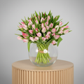 Bouquet of pink tulips in a clear vase on a white background