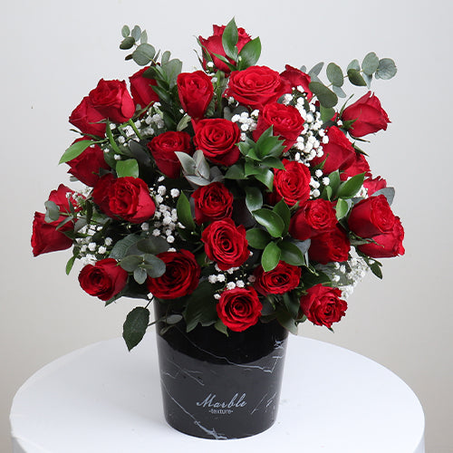 Premium Red Roses in Black Marble vase with green foliage and white fillers for elegant floral arrangements