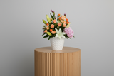 Bouquet of flowers in a white vase on a light gray background