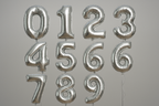 Silver helium balloons in the shape of numbers 0 through 9 in a square format