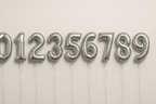 Silver helium balloons in the shape of numbers 0 through 9