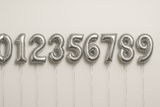 Silver helium balloons in the shape of numbers 0 through 9