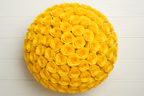 Yellow rose ball on a white wooden surface